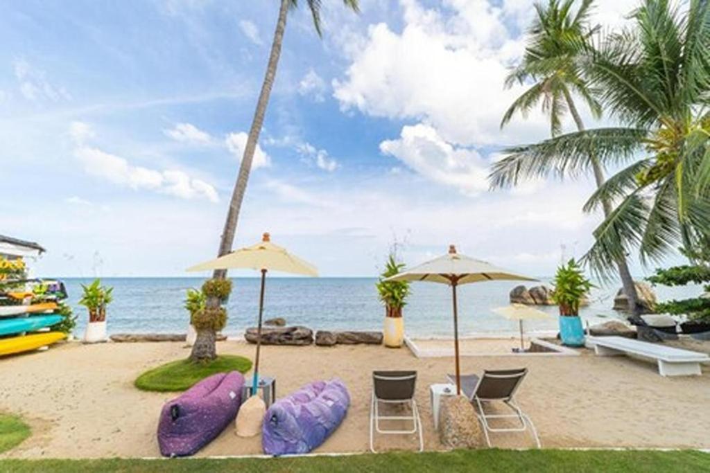 a beach with chairs and umbrellas and the ocean at The Rock Samui Poshtel Lamai Beach in Lamai