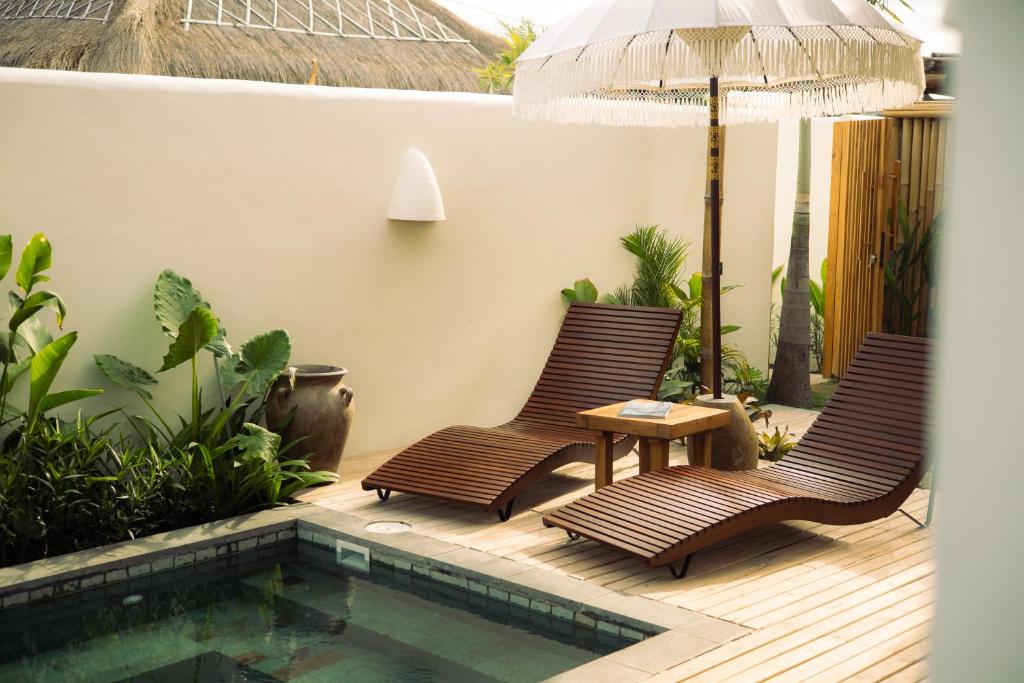 Dos sillas y una mesa junto a una piscina. en Irama Surf Villas, en Sekongkang Bawa