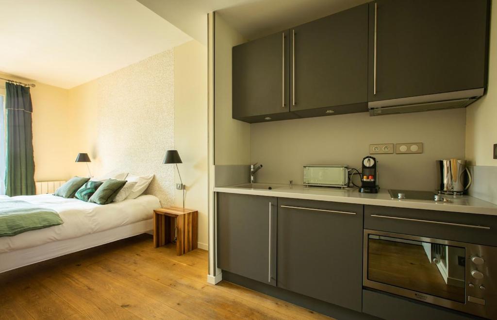 a bedroom with a bed and a kitchen with a microwave at La Villa Fleury - La Nacre in Limoges