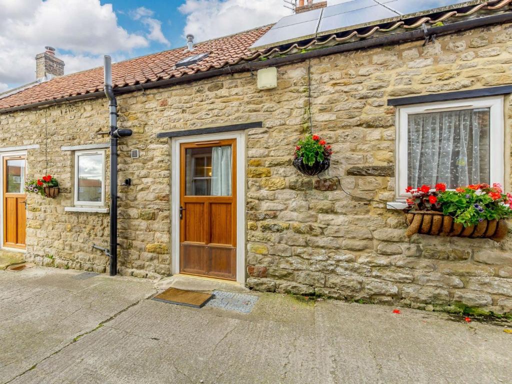 a stone cottage with a wooden door and windows at 3 Bed in Newton-on-Rawcliffe 88958 in Newton