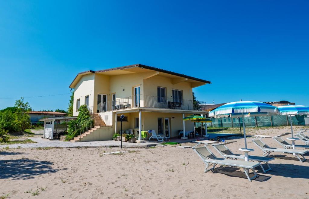 a house on the beach with chairs on the sand at Villa Serena in Rosolina Mare