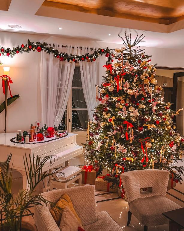 a christmas tree in a living room with a piano at Mamaison Le Regina Boutique Hotel in Warsaw