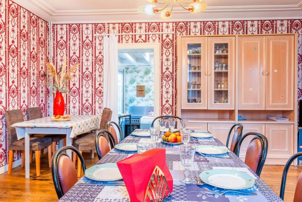 a dining room with tables and chairs and a kitchen at Gîte de l'ouvroux in Montournais