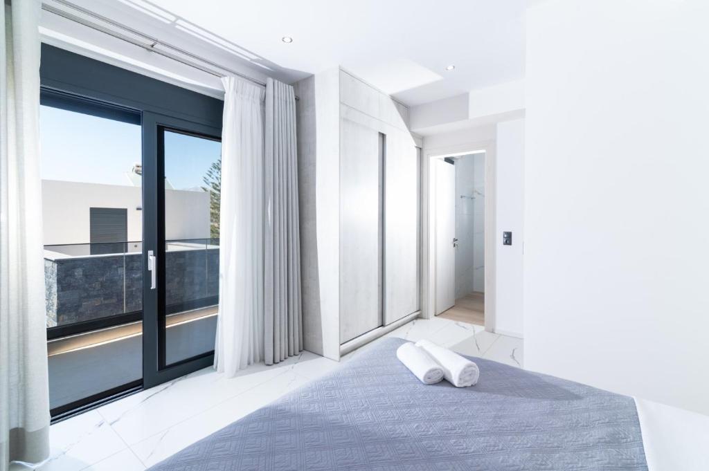 a bedroom with a bed and large windows at Villa Melora in Pitsidia