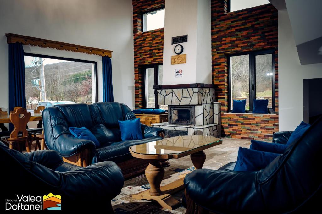 a living room with blue leather furniture and a fireplace at Mai cu Mot Doftana Luxury Chalets in Trăisteni