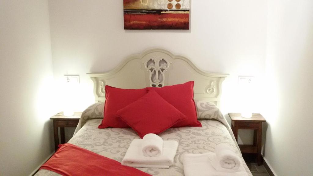 Una cama con almohadas rojas y toallas. en El Pilar de Don Gregorio, en Pereruela