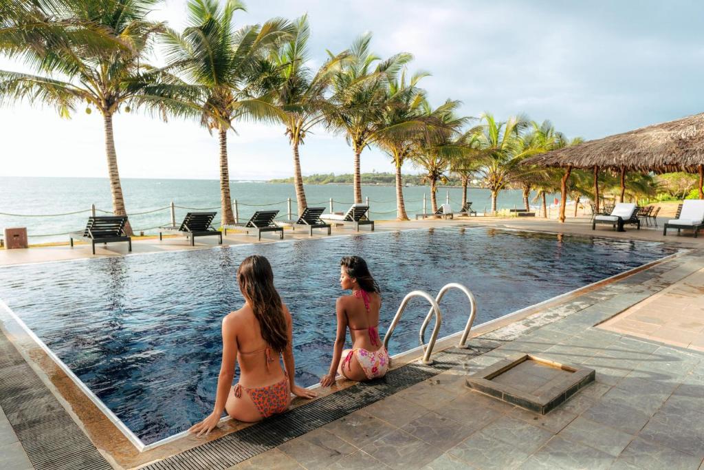 two girls sitting in the infinity pool at a resort at Peacock Beach Resort- Hambantota in Hambantota