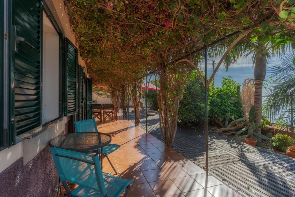 a balcony with a table and chairs and a view of the ocean at Flora Garden House by HR Madeira in Estreito da Calheta