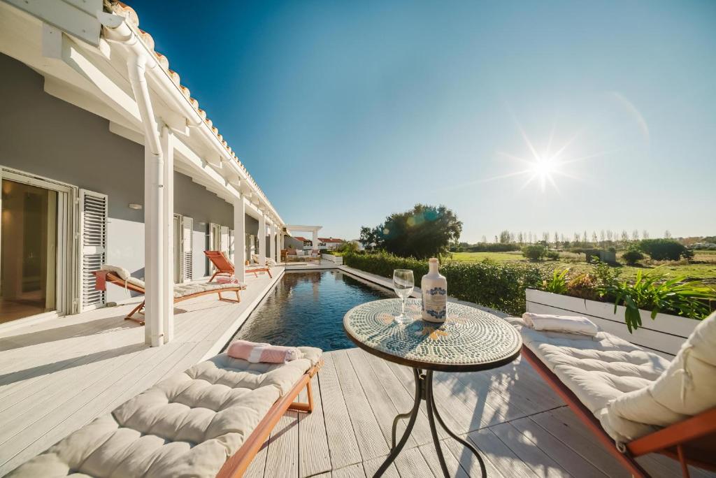 un patio con tavolo e sedie e una piscina di Villa Verso Comporta - NEW! a Monte da Carrasqueira