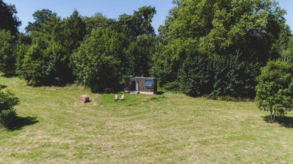 una pequeña cabaña en medio de un campo con árboles en Parcel Tiny House I Richecourt vue Prairie, en Mesbrecourt-Richecourt