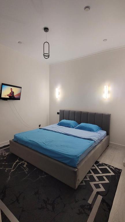 a bedroom with a bed with blue sheets and blue pillows at Однокомнатная квартира посуточно in Astana