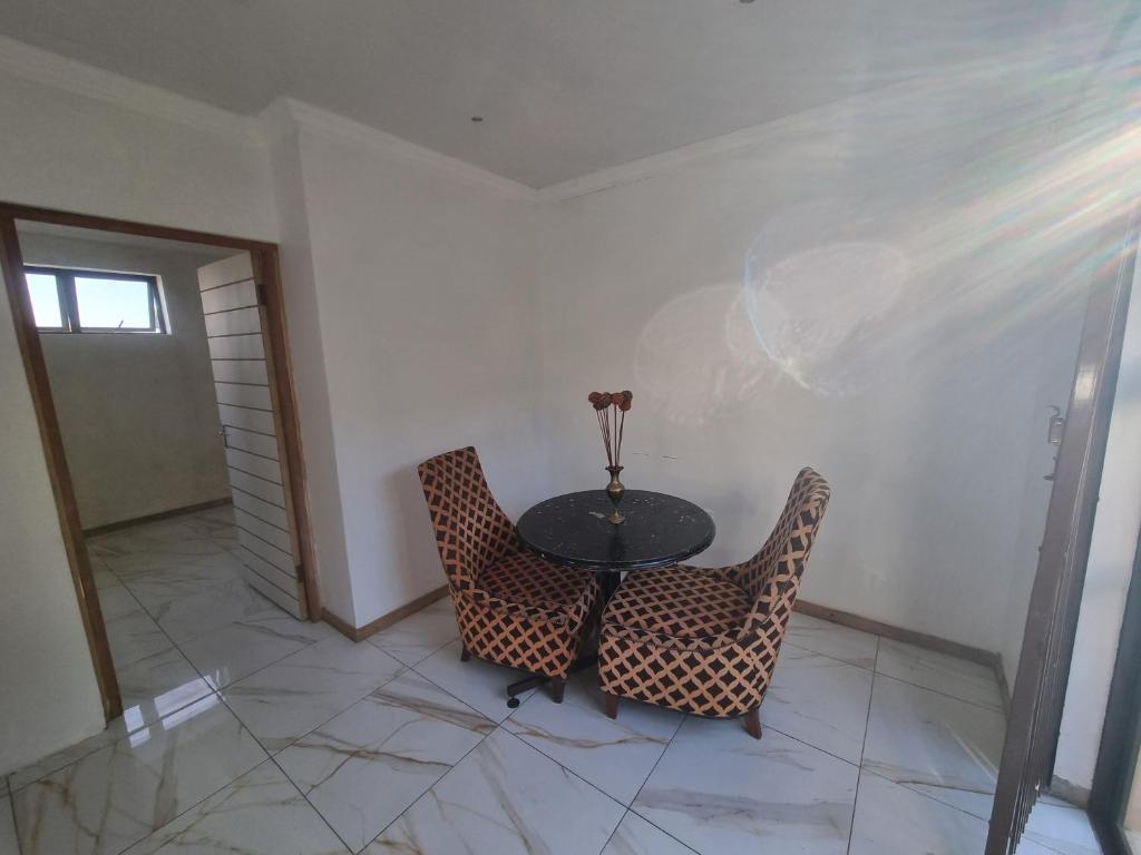 una sala da pranzo con un tavolo e due sedie di Bird Whistle a Zeekoevlei