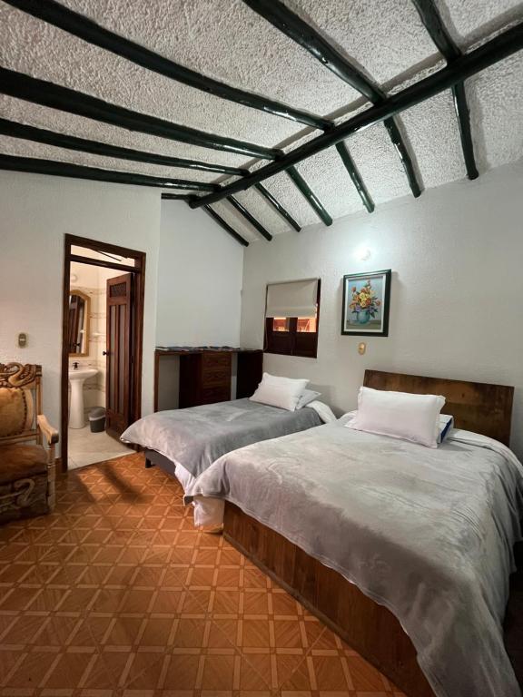 a bedroom with two beds in a room at Hotel Santa Lucia de Cucaita in Cucaita