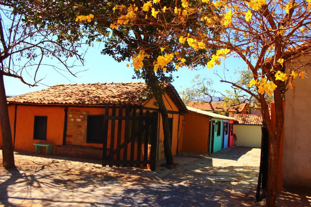 a building with a gate next to a tree at Pousada Vila Cipó in Serra do Cipo