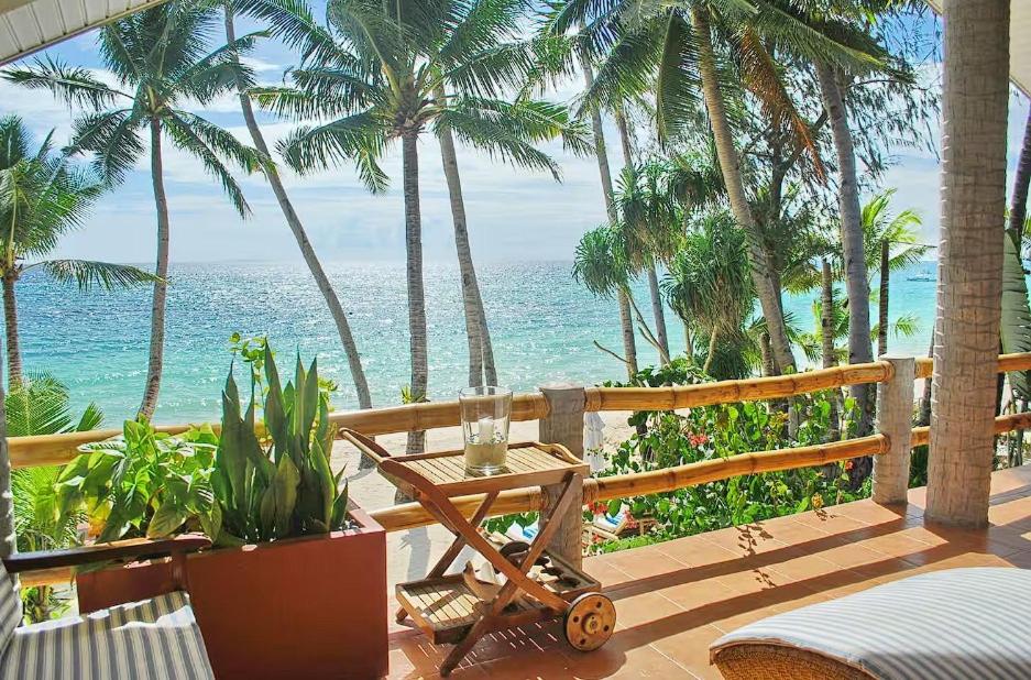 a patio with a table and palm trees and the ocean at Right along the shoreline ! in Boracay