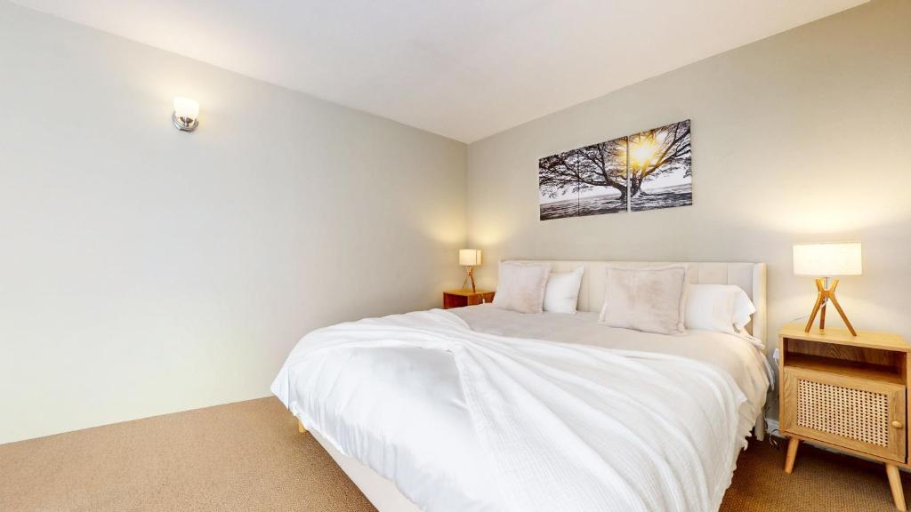 a bedroom with a large white bed with a picture on the wall at Western Slopes Villas #7 condo in Mammoth Lakes