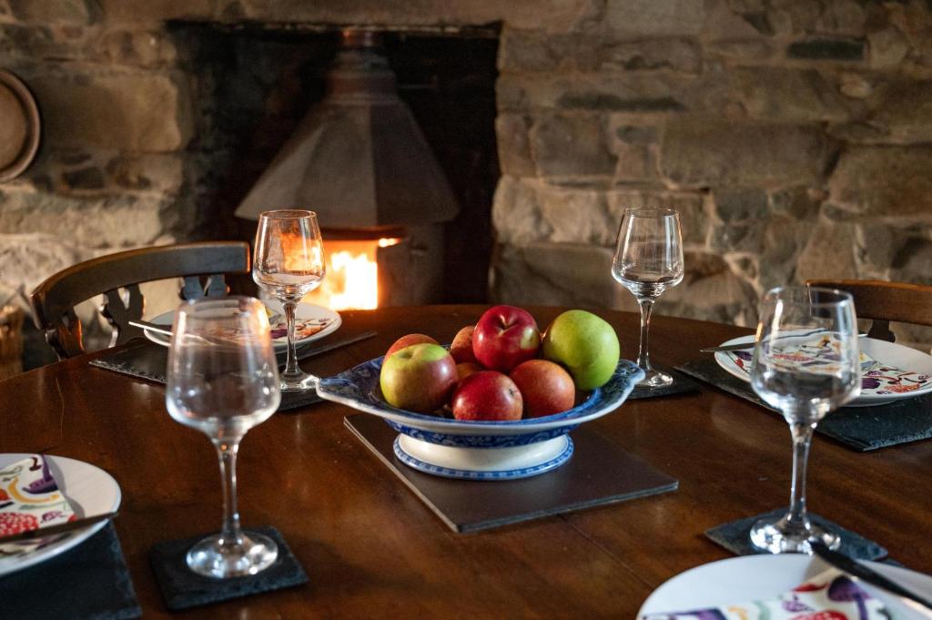 a table with a bowl of apples and wine glasses at Panoramic Mountain Retreat - Waen Fechan - 4x4 access only in Dolgellau