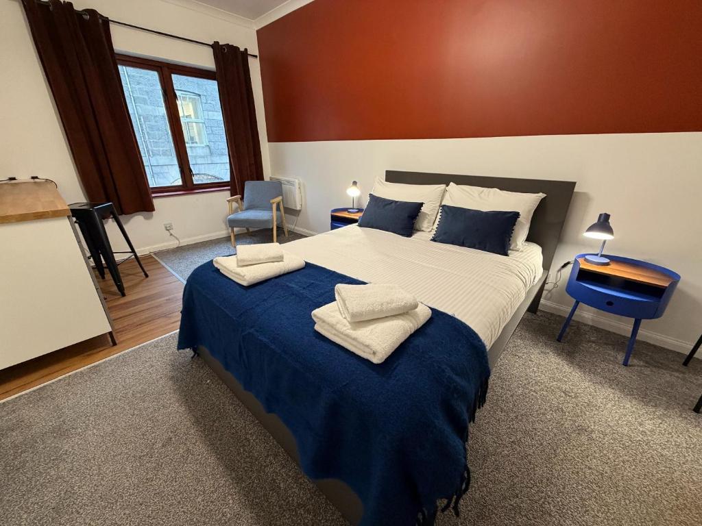 a bedroom with a large bed with a blue blanket at Core Citi Lets, Guild Street Rooms in Aberdeen