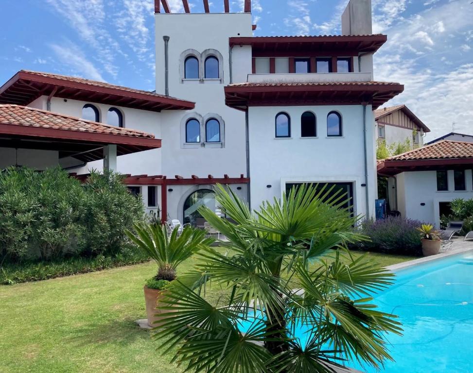 een huis met een palmboom voor een zwembad bij Beautiful house Ciboure pool designed in Ciboure