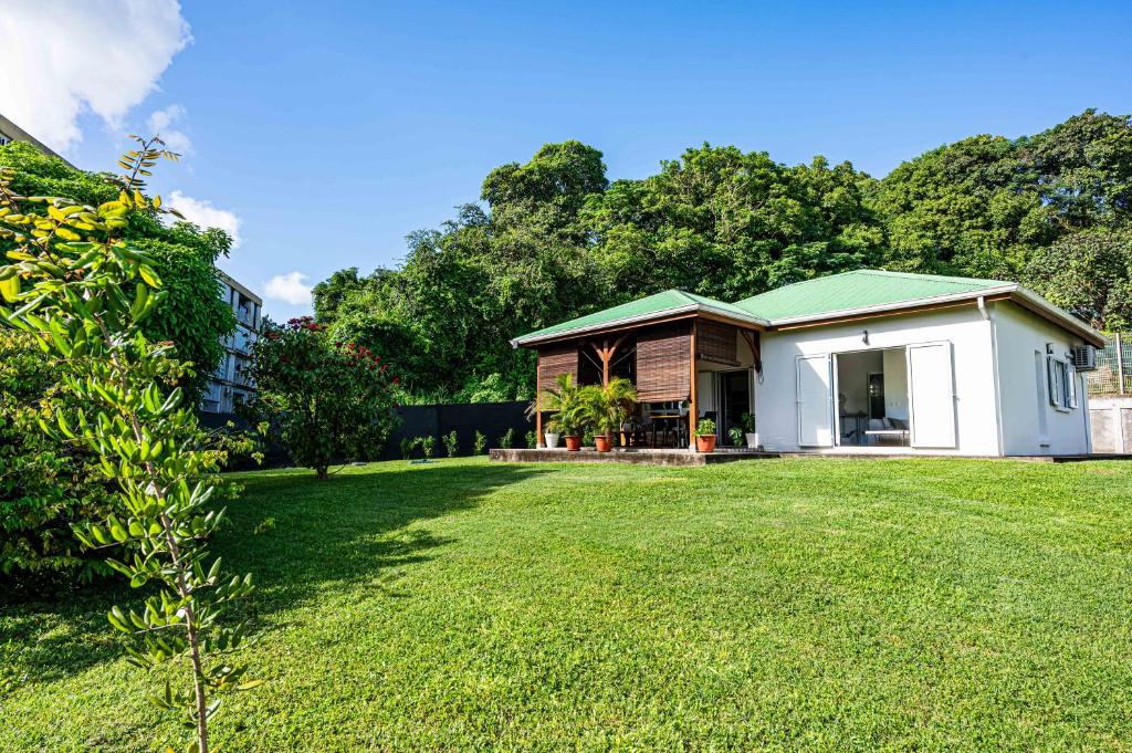 a small house with a green roof in a yard at La Kaz Zen - Cozy house with garden in Les Abymes