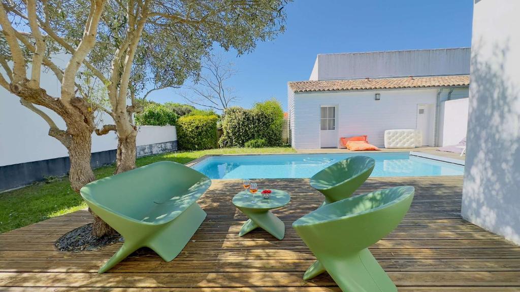 two green chairs and a table next to a pool at Superbe villa avec piscine dans le village de St Clément in Saint-Clément-des-Baleines