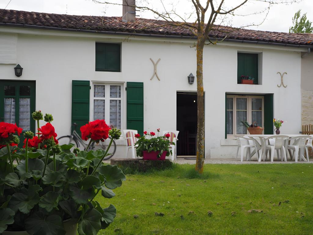 ein weißes Haus mit roten Blumen im Hof in der Unterkunft Gite La Ferme - Les Gites Du Moulin in Saint-Hilaire-la-Palud