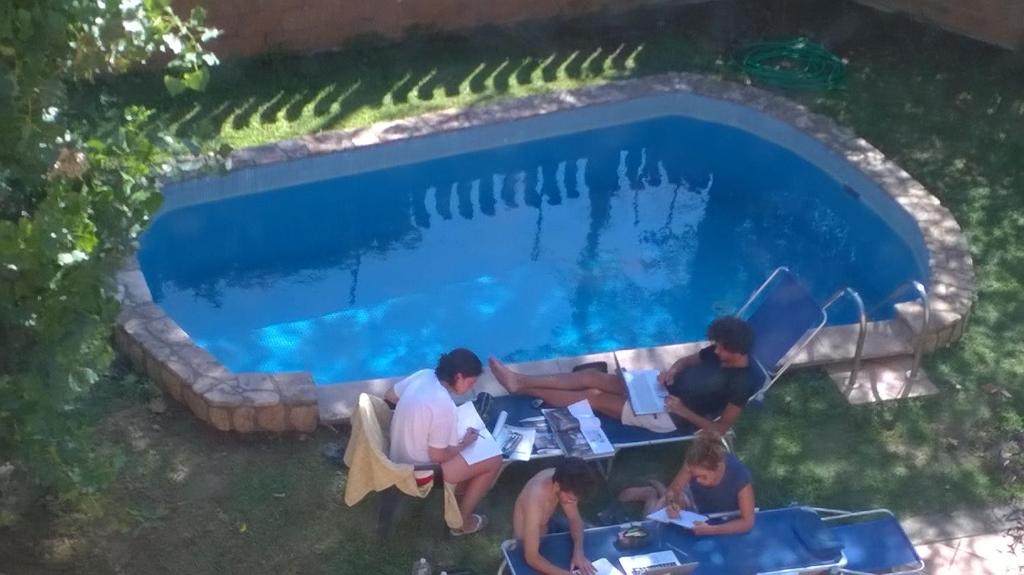 un grupo de personas sentadas alrededor de una mesa junto a una piscina en Villa Cardinal Apartments, en Tívoli