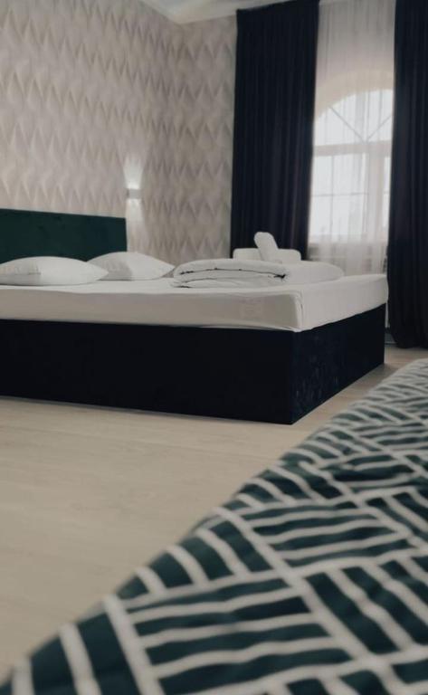 a bed in a bedroom with a black and white rug at Meiman Hotel in Aktobe