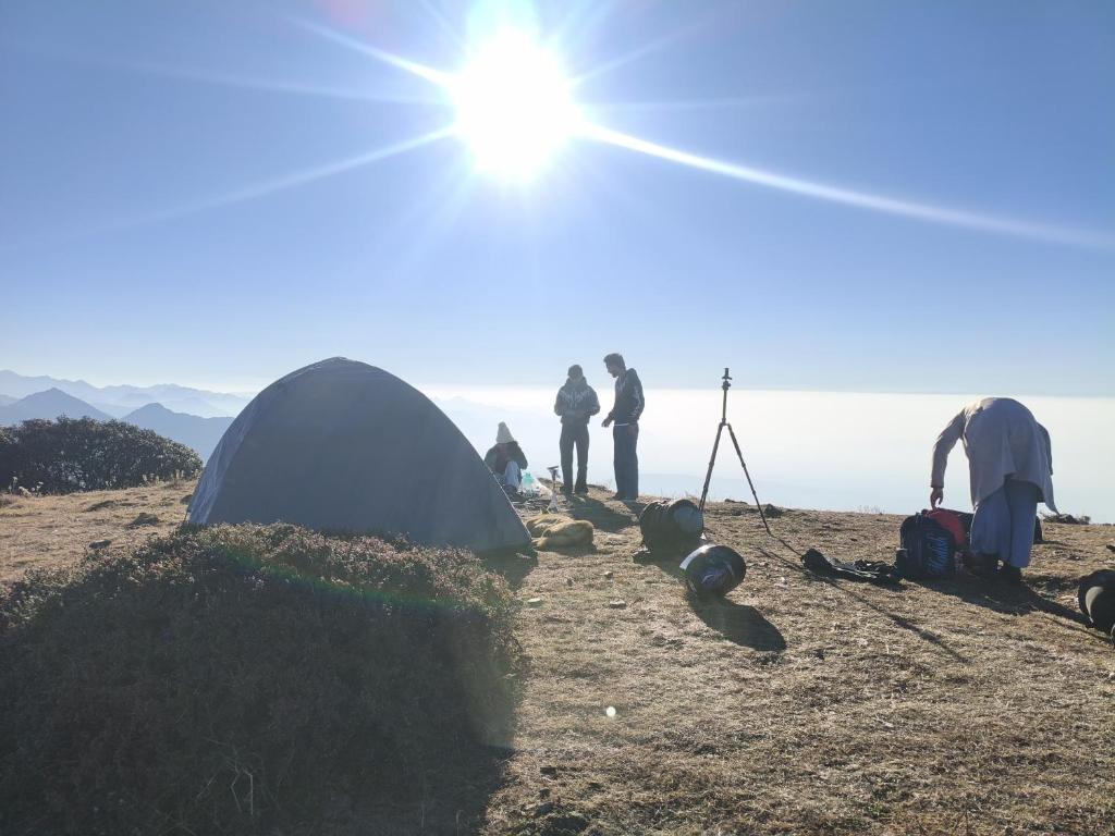 a group of people standing next to a tent on a hill at Himalayan Cloud Door Camps in Dehradun