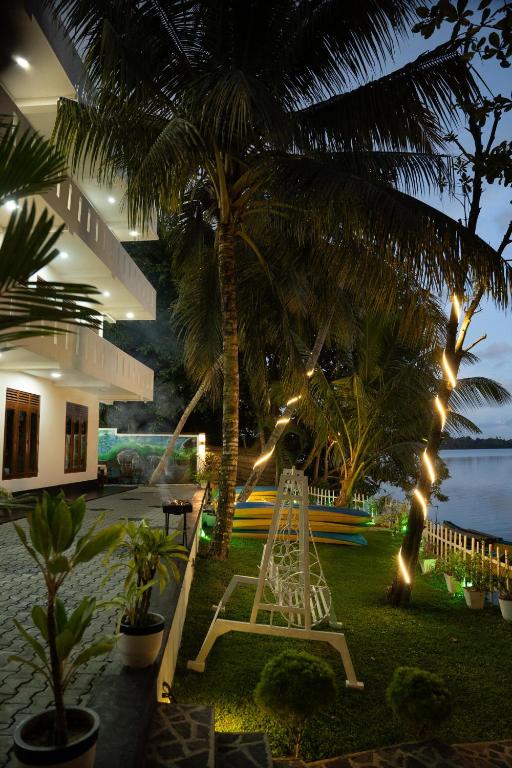 a garden with a ladder and palm trees and lights at Scenery River Star Hotel in Hikkaduwa