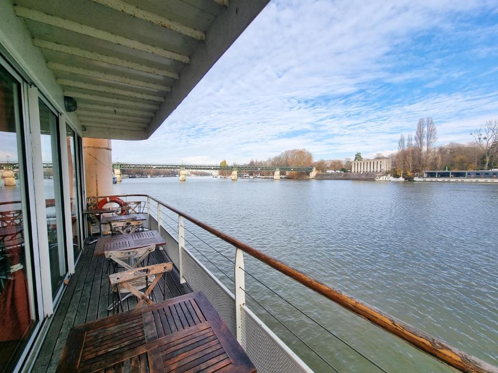 a boat deck with benches and a view of a river at EXIGEHOME-Large houseboat with spa near Paris in Saint-Cloud