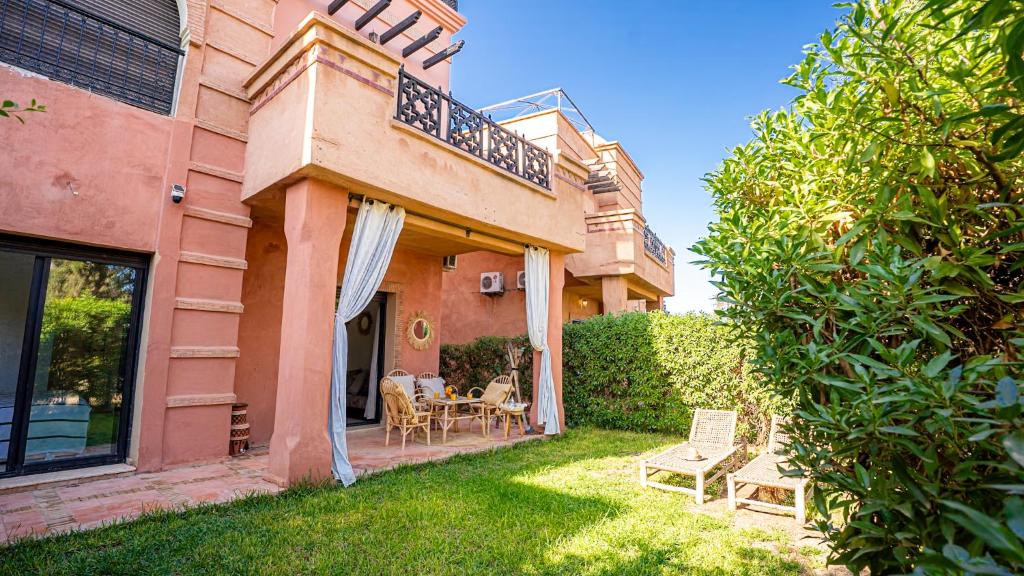 a house with a yard with chairs and a balcony at Appartement cosy, calme, détente, piscines, jardins in Marrakech