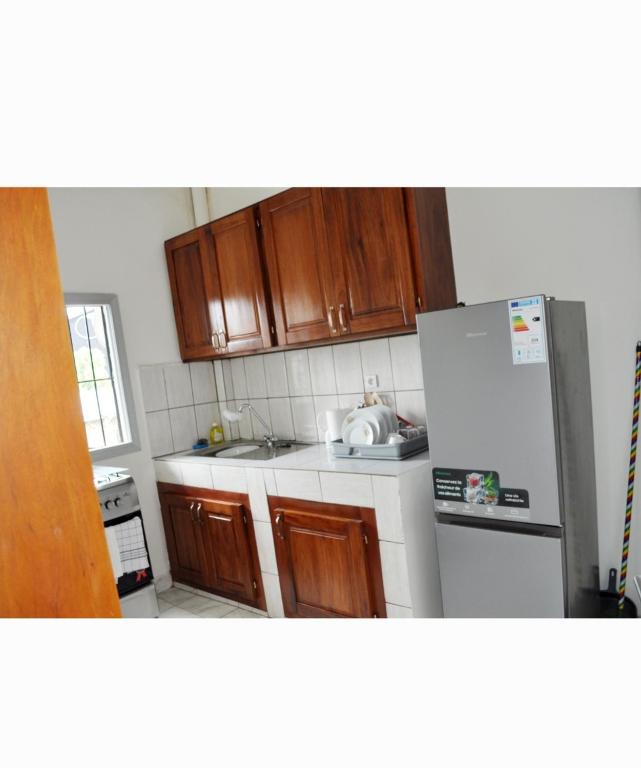 a kitchen with wooden cabinets and a refrigerator at Résidence 2B in Douala