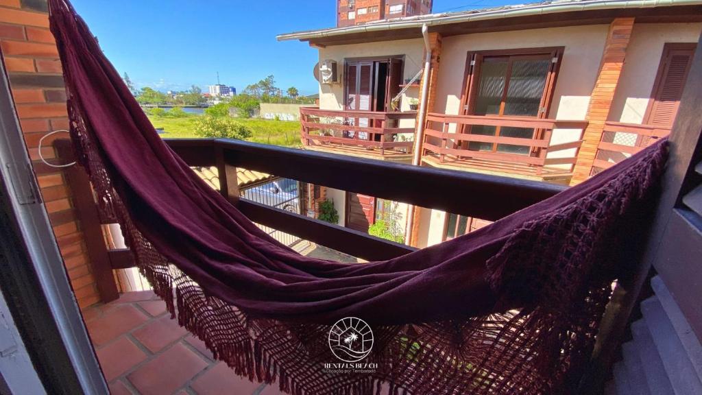 una hamaca en el balcón de una casa en Sobrado aconchegante próximo do mar, en Passo de Torres