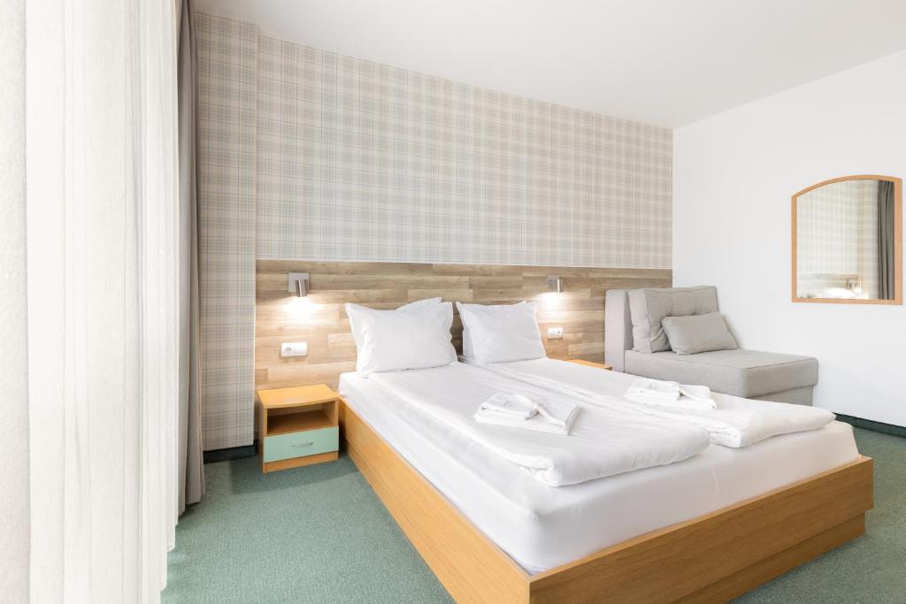 a bedroom with a large white bed and a chair at Hotel Iceberg Bansko in Bansko