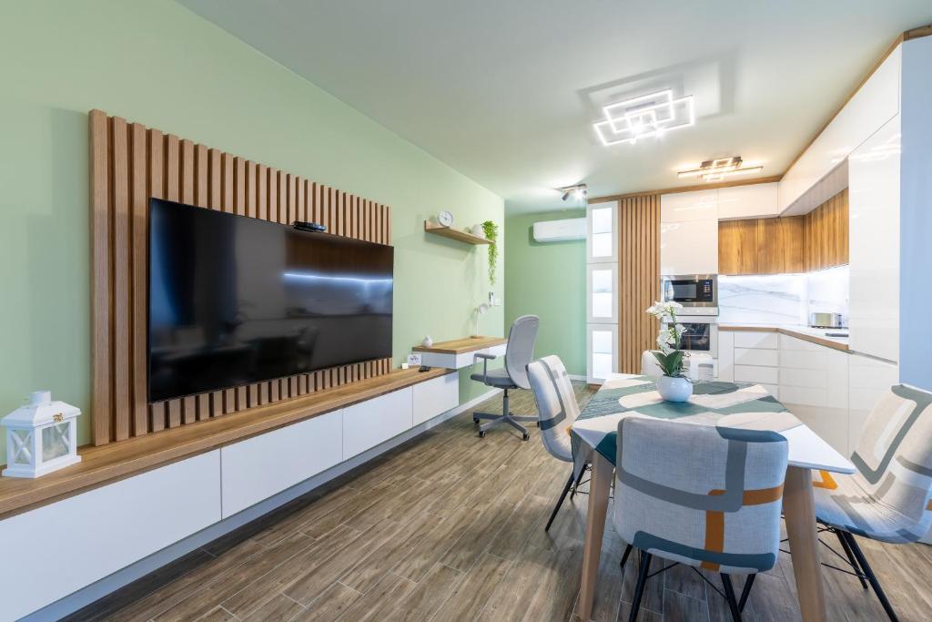 Stylish 1BR Flat Garden Balcony Parking في مدينة فارنا: غرفة معيشة مع طاولة طعام وتلفزيون كبير