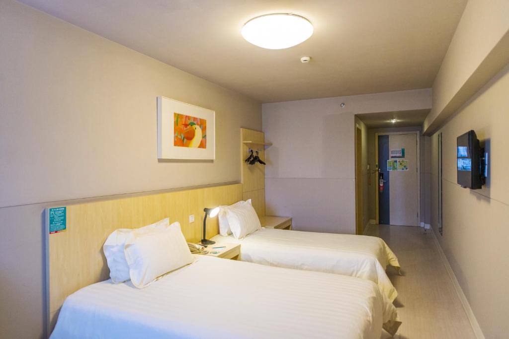 Jinjiang Inn Select Huizhou West Lake Pedestrian Street في هويزو: غرفة فندقية بسريرين وتلفزيون
