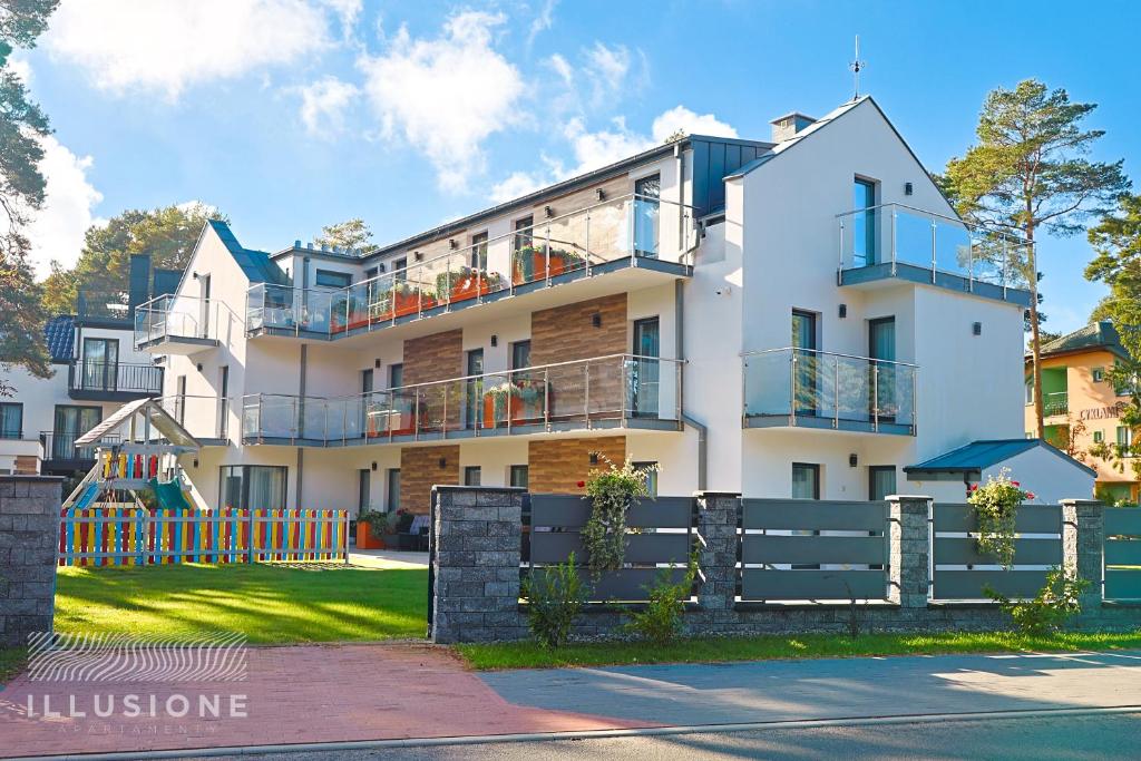 Un edificio de apartamentos con balcones y una valla. en Illusione, en Pobierowo