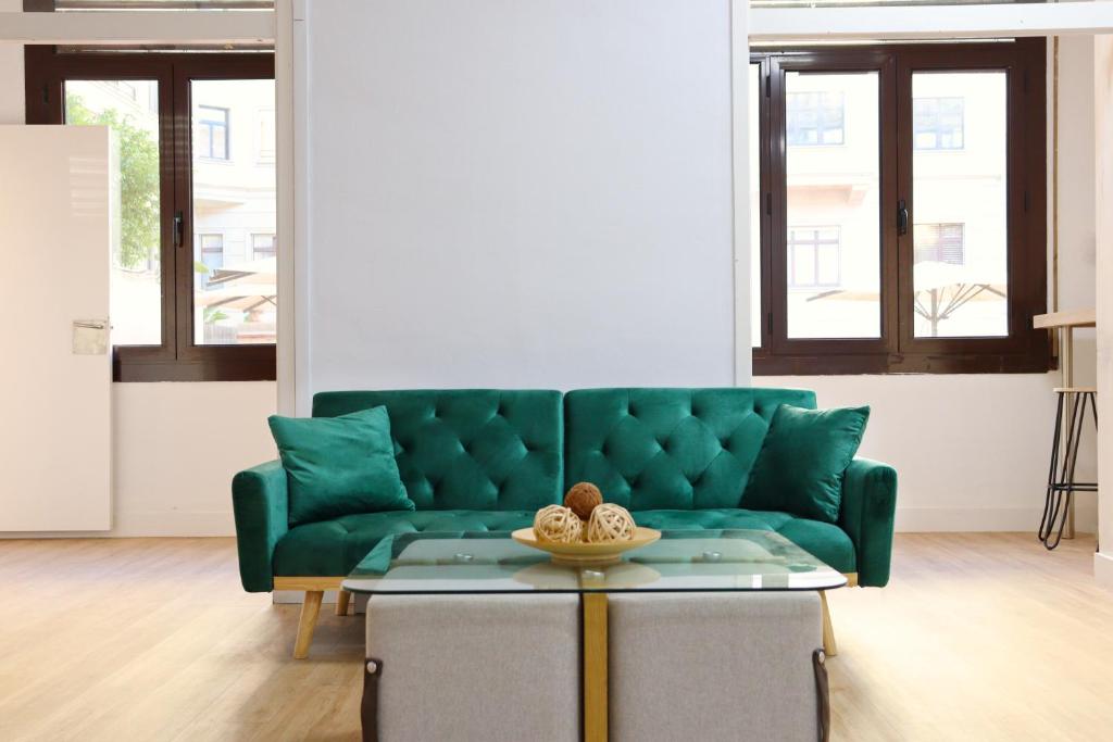 a green couch in a living room with a table at lullaby by hamilton in Barcelona