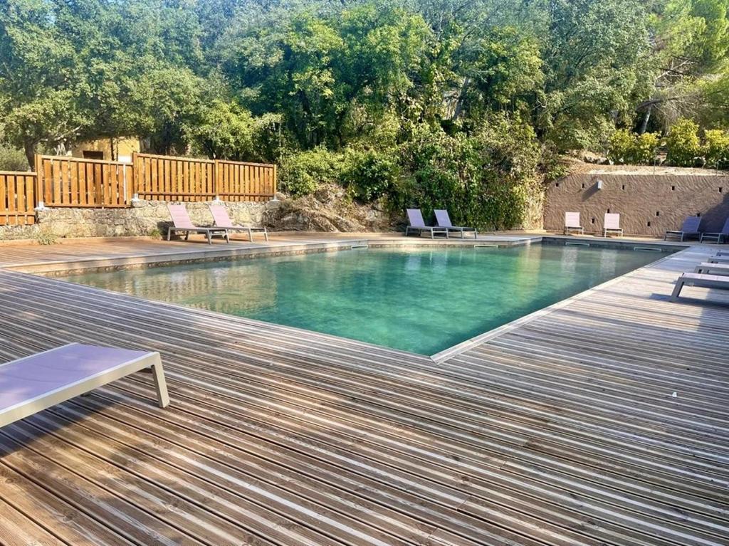 a swimming pool with chairs and a wooden deck at ZEcamping 3 étoiles animaux acceptés in Sartène