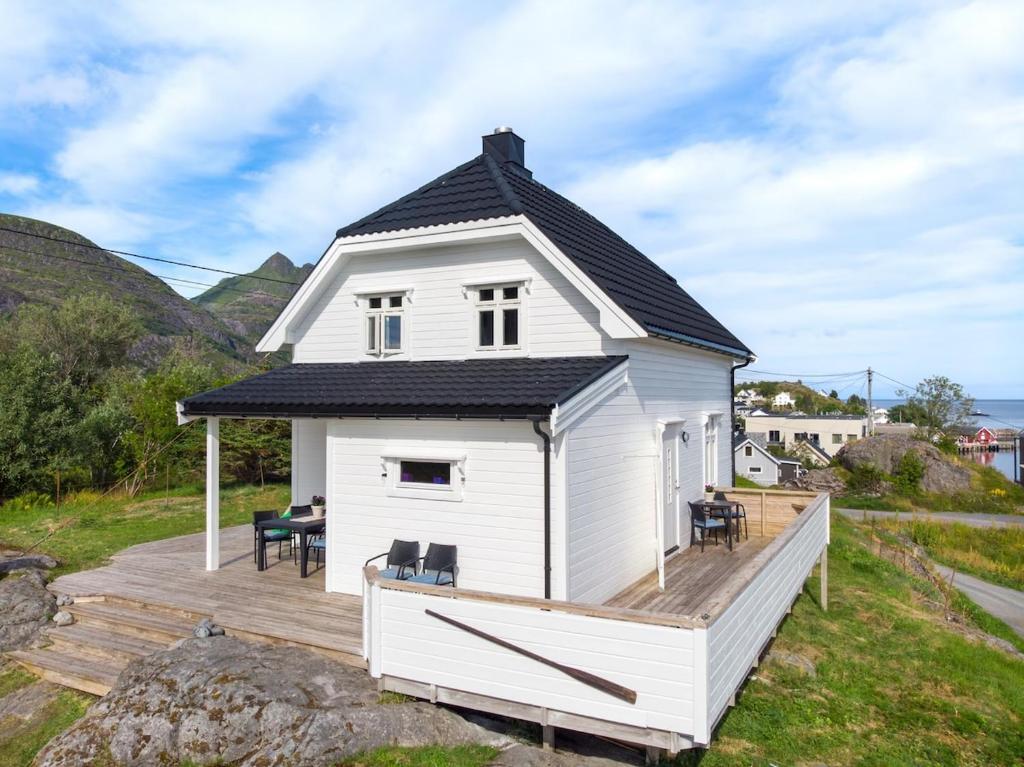 a white house with a black roof on a wooden deck at Littahuset in Moskenes
