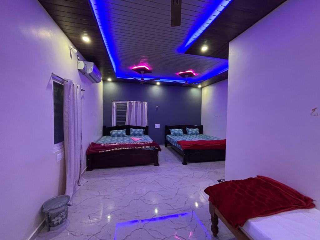 two beds in a room with purple lights at Ananya home stay hampi in Hampi