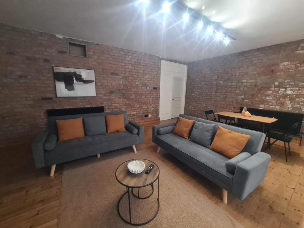Stylish modern 2 bedroom apartment في سندرلاند: غرفة معيشة بها أريكتان وجدار من الطوب