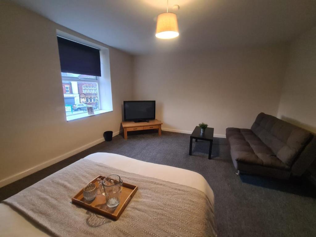 a bedroom with a bed and a couch and a television at The Green in Sunderland