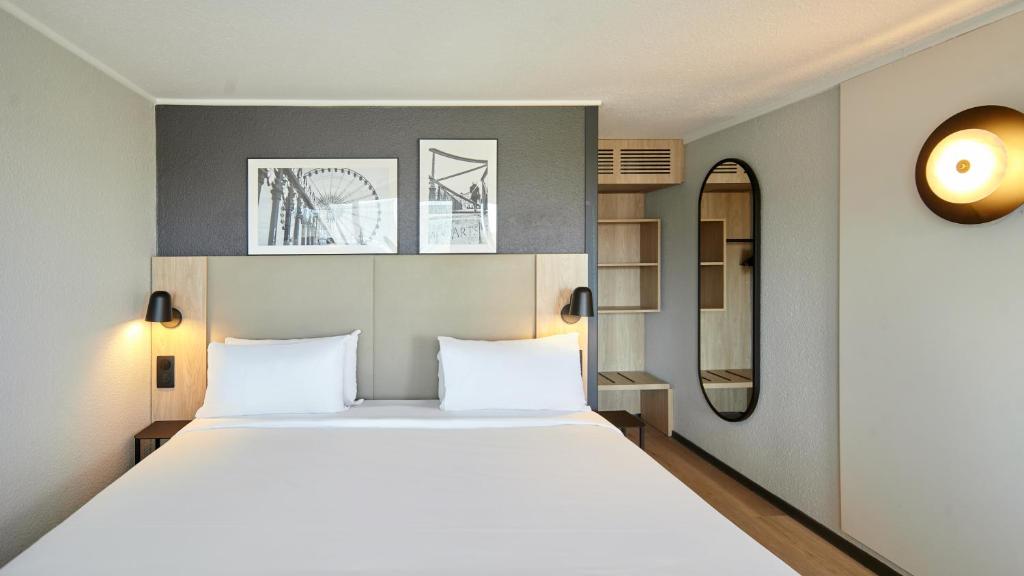 a bedroom with a large bed with white sheets at Campanile NATURE - Vierzon in Vierzon