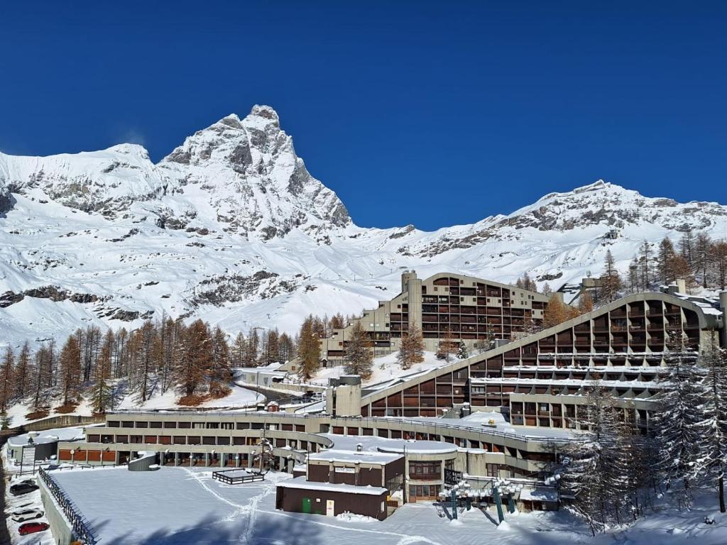 un edificio nella neve con una montagna sullo sfondo di Casa Preziosa Cielo Alto a Breuil-Cervinia