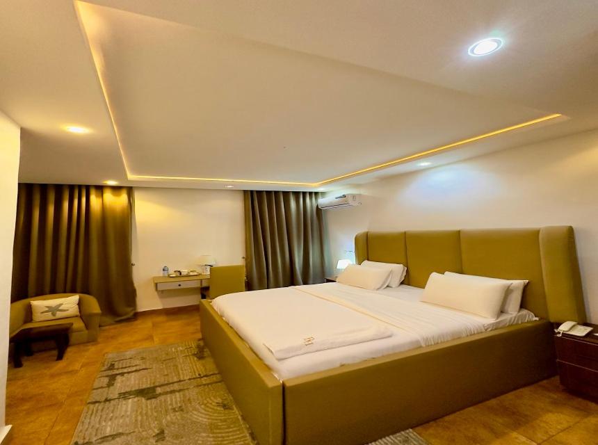 Un dormitorio con una cama grande y un escritorio. en Beauties And Hunks hotel - B&H, en Abuja