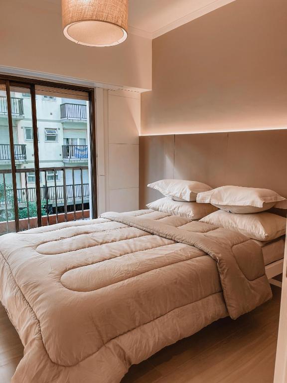 Una cama grande en un dormitorio con una ventana grande. en Bolivar, en Mar del Plata