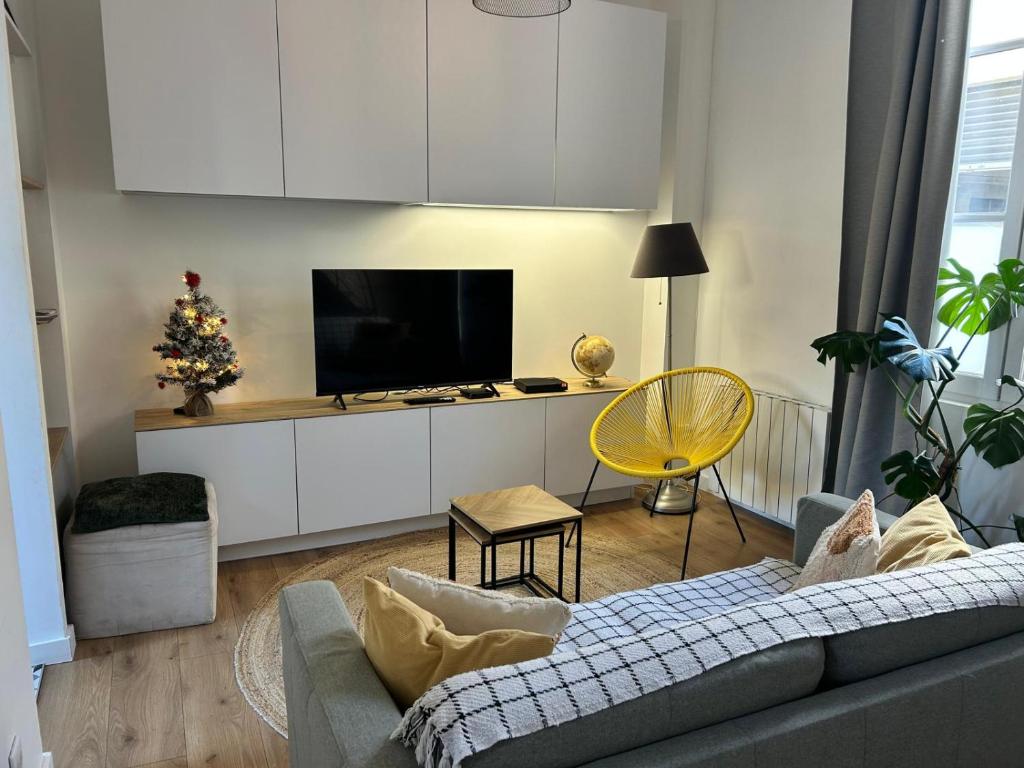 ein Wohnzimmer mit Sofa und Fernseher in der Unterkunft Maison Cosy en centre-ville in Libourne