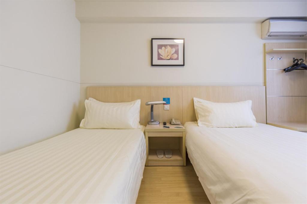 a room with two beds and a desk with a lamp at Jinjiang Inn Harbin METRO in Harbin